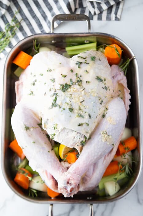 Top view of a raw Whole Turkey on a baking tray with vegetables