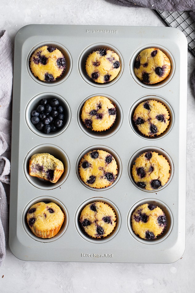 Overhead view of Lemon Blueberry Muffins in a tin with blueberries in one cup