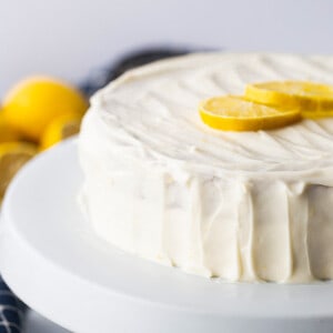 Side shot of a frosted layered healthy lemon cake on a white plate