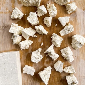 Torn tofu pieces on a wooden cutting board
