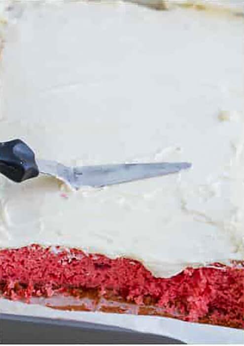 Spatula spreading icing on.a strawberry cake