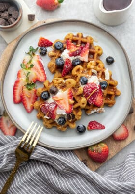 Top view of four gluten free waffles on a grey plate with a gold fork