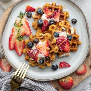 Top view of four gluten free waffles on a grey plate with a gold fork