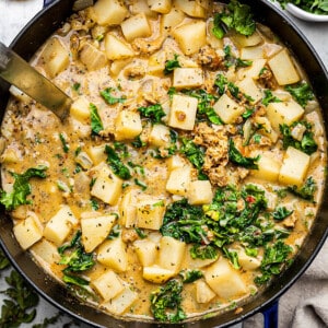Vegetable broth and diced potatoes and kale in a blue dutch oven / pot