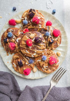 6 Low Carb Paleo Keto Pancakes with mixed berries on a ceramic cream plate