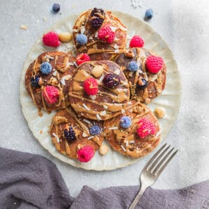 6 Low Carb Paleo Keto Pancakes with mixed berries on a ceramic cream plate