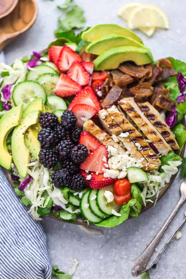 Ensalada de pollo a la parrilla con bayas de verano: un almuerzo o cena fácil y saludable, perfecto para noches de semana ajetreadas o cenas de verano. Hecho con aguacate, pepino, tocino, fresas, moras y tomates con una vinagreta de limón picante, fresca y sabrosa.