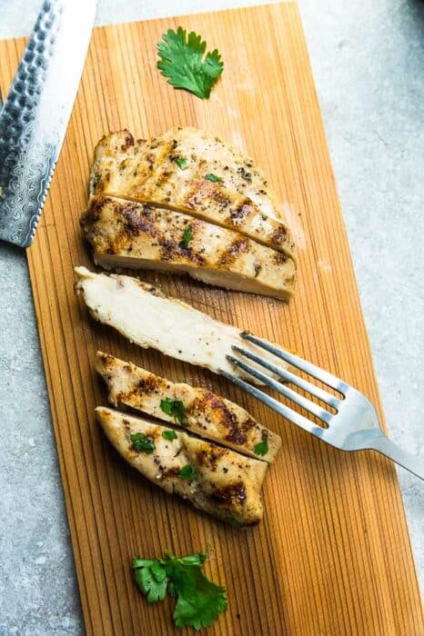 A Grilled Chicken Breast Sliced into Five Pieces on a Cutting Board