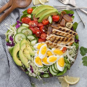 Chicken Cobb Salad has all the classic flavors of the popular favorite with a simple vinaigrette. Made with lettuce, tomatoes, bacon, cucumber, avocado and cheese – perfect for lunch or your next potluck!