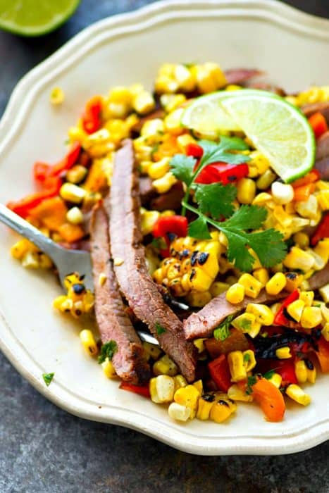 Grilled skirt steak with charred corn and pepper salad on a plate
