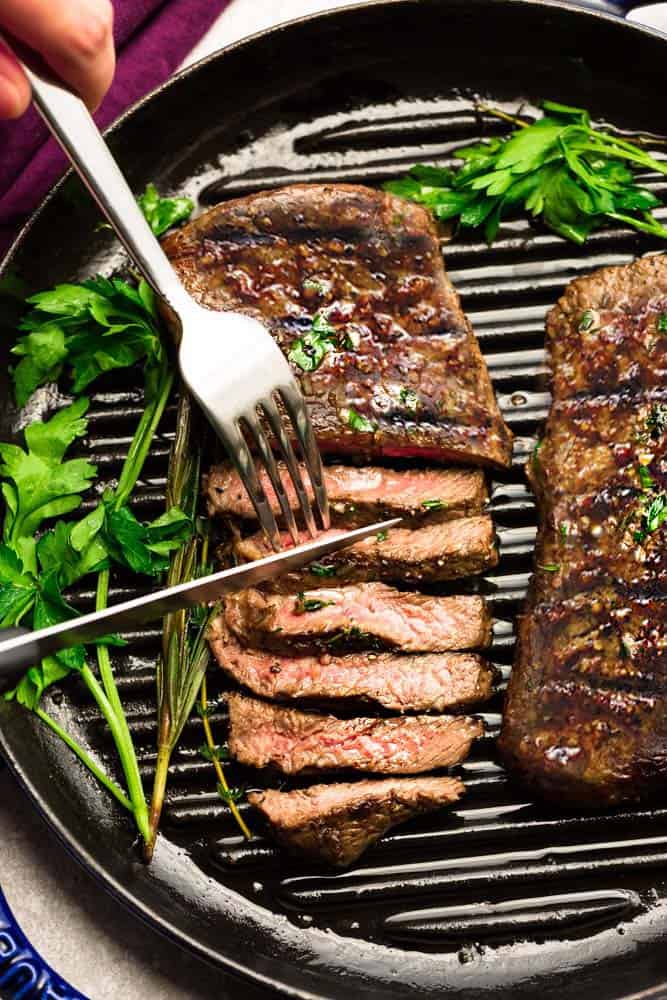 Perfectly grilled teak on grill top with fork and knife.