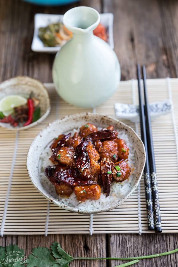 A serving of General Tso's Chicken over white rice in a bowl with chopsticks