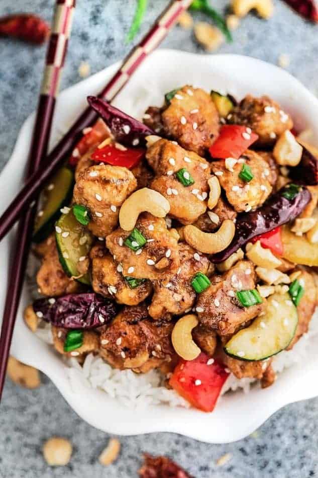 Top view of a serving of Kung Pao Chicken over rice in a bowl topped with cashews