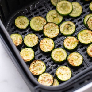Side shot of air fryer zucchini rounds in an air fryer basket