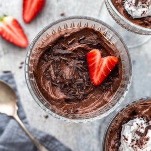 Avocado Chocolate Pudding in three glass jars with a strawberry