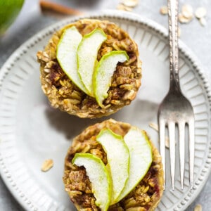 Two baked apple oatmeal cups on a white plate with a fork