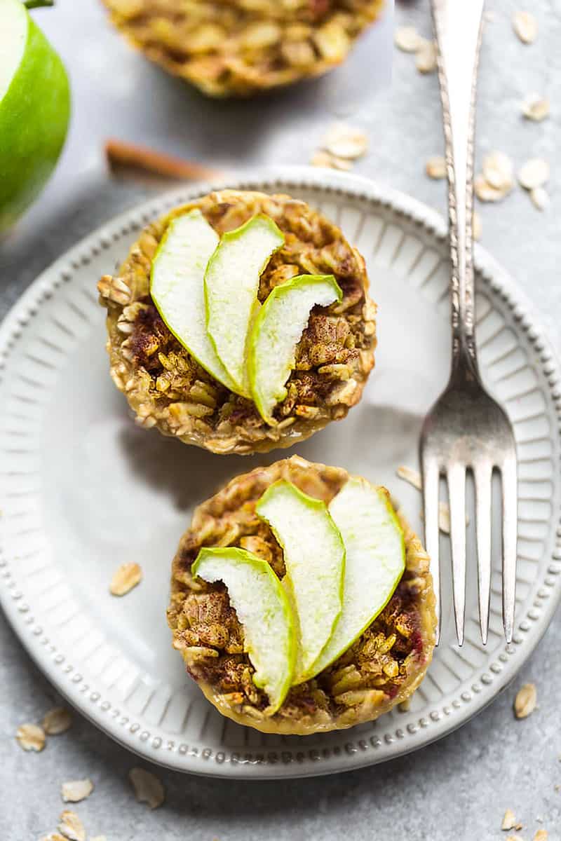 Two baked apple oatmeal cups on a white plate with a fork