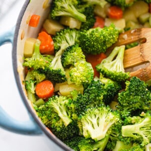 A pile of fresh carrots, broccoli, celery and potatoes in a dutch oven pot