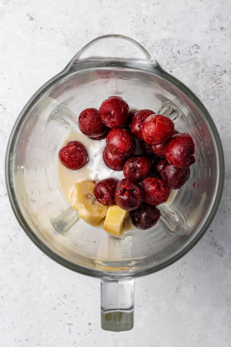 Top shot of frozen cherries, coconut cream and milk in a blender