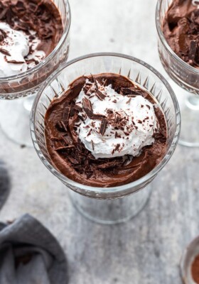 A serving of healthy chocolate mousse topped with whipped cream in a clear goblet.