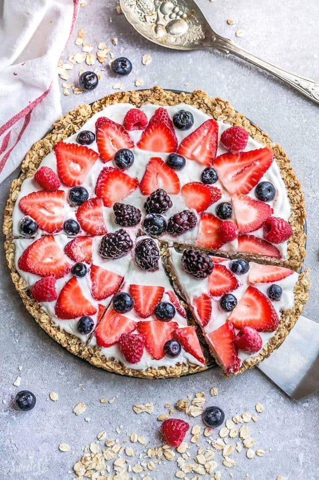 Top view of Red White & Blue Breakfast Pizza on parchment paper with a slice cut out for berry recipes.