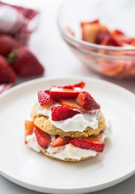 Portrait view of one gluten free strawberry shortcake on a white plate