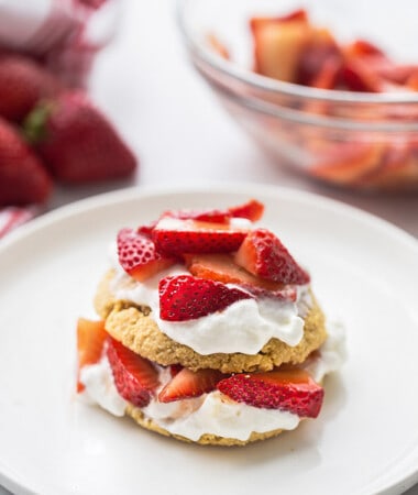 Portrait view of one gluten free strawberry shortcake on a white plate