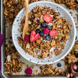 Top view of healthy granola in a white bowl on a baking sheet