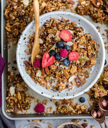 Top view of healthy granola in a white bowl on a baking sheet