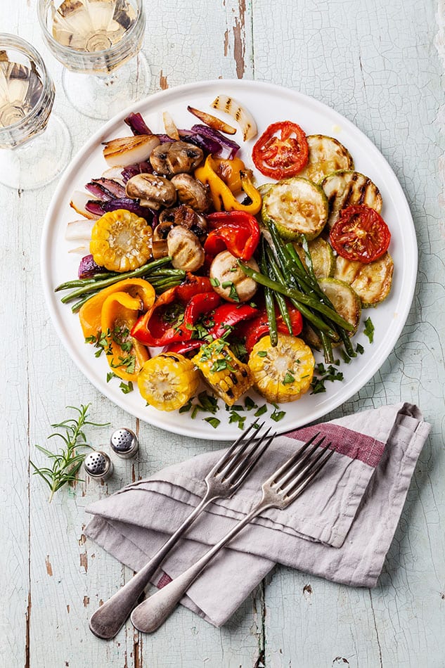 Grilled vegetables on the white plate on blue textured background