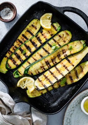 Top view of a batch of grilled zucchini slices on cast iron grill.