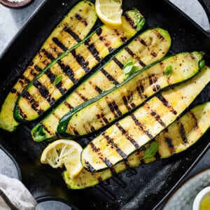 Top view of a batch of grilled zucchini slices on cast iron grill.