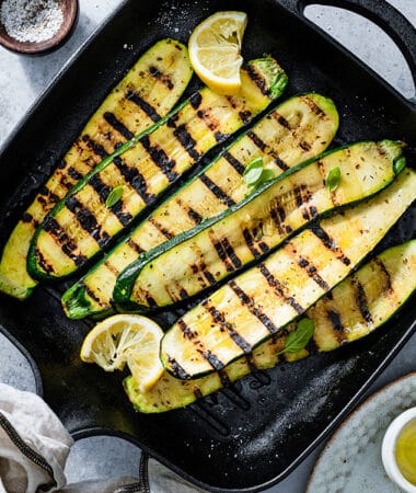 Top view of grilled zucchini slices on cast iron grill.