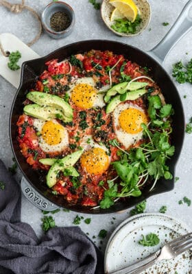 Top view of healthy shakshuka in a grey cast-iron skillet on a grey background with forks