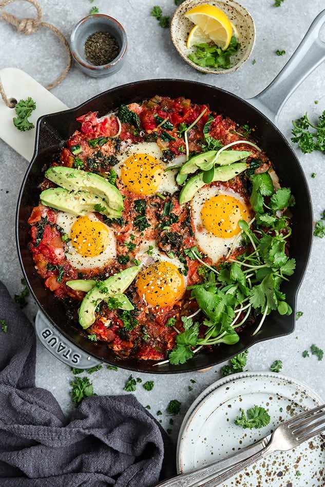 Top view of healthy shakshuka in a grey cast-iron skillet on a grey background with forks