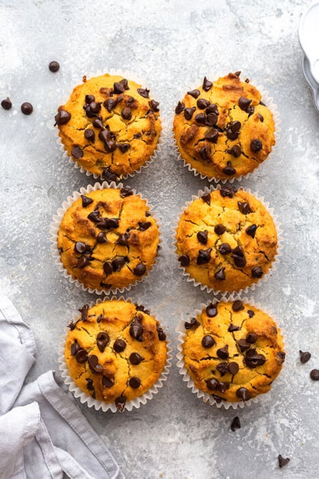 Top view of 6 healthy pumpkin muffins scattered on a grey background