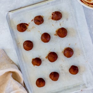 Overhead view of chocolate truffle filling balls on a parchment-lined baking sheet