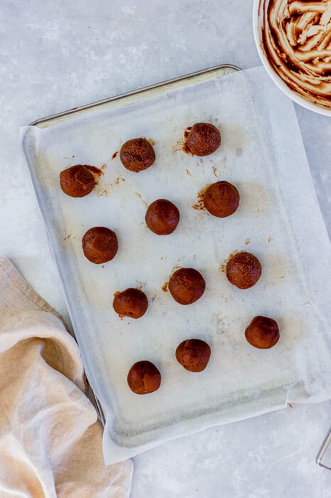 Overhead view of chocolate truffle filling balls on a parchment-lined baking sheet