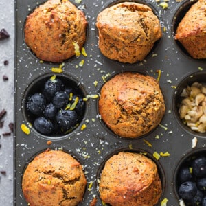 Six Lemon Poppy seed Muffins in a muffin pan with blueberries