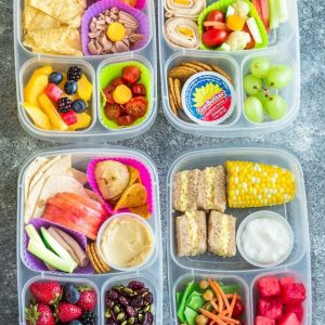 Four school lunch ideas in clear bento lunchboxes on a grey background