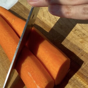 A knife chopping two carrots on an angle