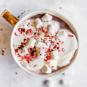 Top close-up view of easy peppermint hot chocolate in a white mug with marshmallows and candy canes