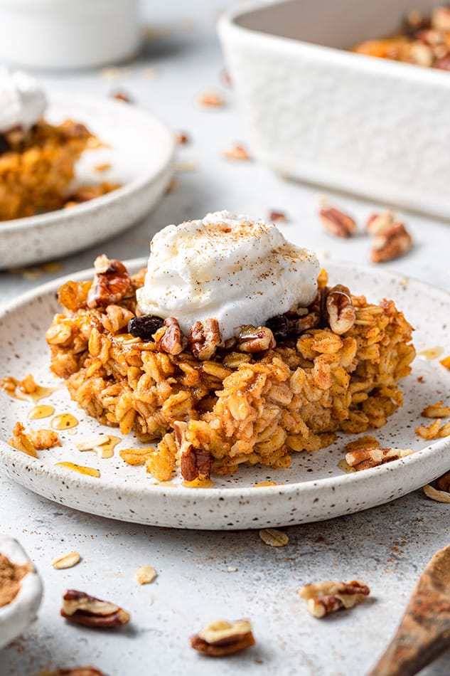 A slice of pumpkin oatmeal bake on a plate with a dollop of dairy-free yogurt on top