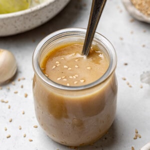 45 degree view of blended sesame dressing in a glass jar with a spoon