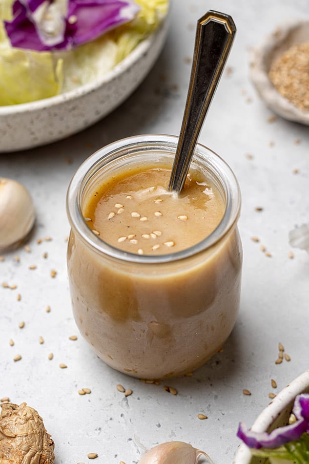 45 degree view of blended sesame dressing in a glass jar with a spoon