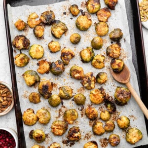 Top shot of a baking sheet lined with parchment paper with roasted smashed brussels sprouts