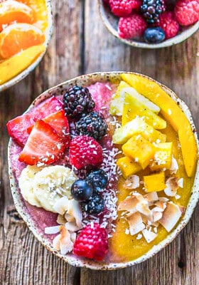 Top view of an eaasy mango smoothie recipe in a white bowl topped with fresh berries