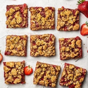 Top view of 9 strawberry crumb bars on on a white background