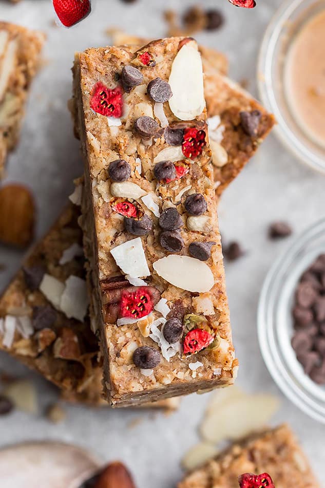 Top close-up view of Strawberry Granola Bars stacked on a grey background for berry recipes round-up.