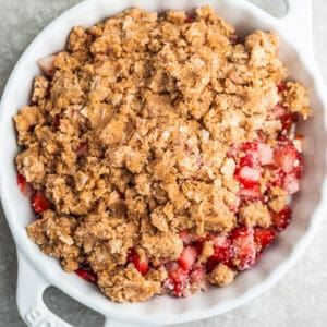 Top view of strawberry rhubarb crisp topping and strawberry filling in a white pie pan